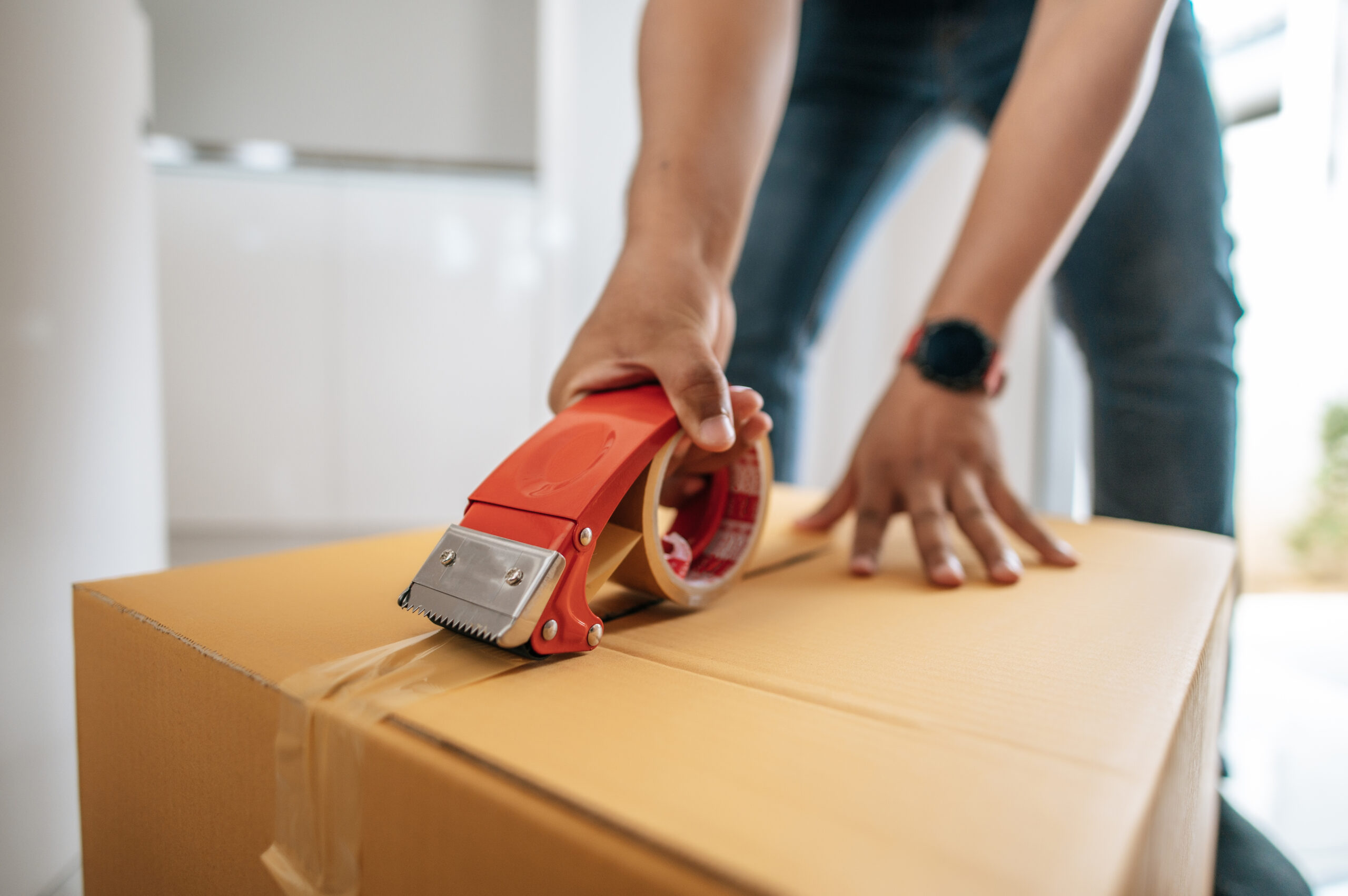 Home male hand sealing big box with glue tape for packing